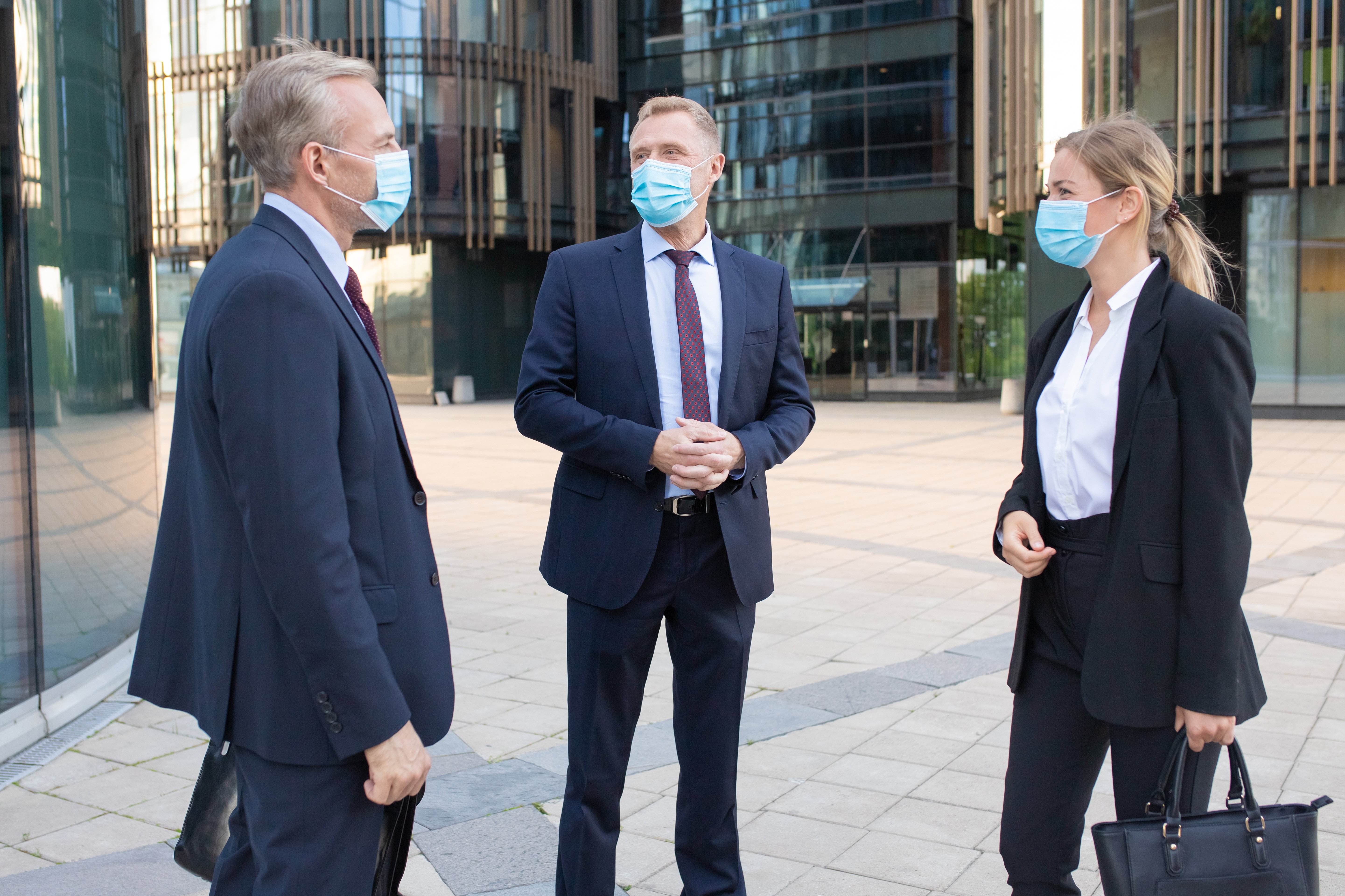 three-professional-business-colleagues-facial-masks-discussing-deal-outside-content-successful-managers-standing-street-talking-about-work-negotiation-protection-partnership-concept-1